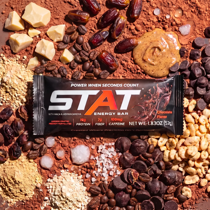 Wrapped STAT Chocolate energy bar on a spread of cocoa beans, chocolate chunks and ingredients