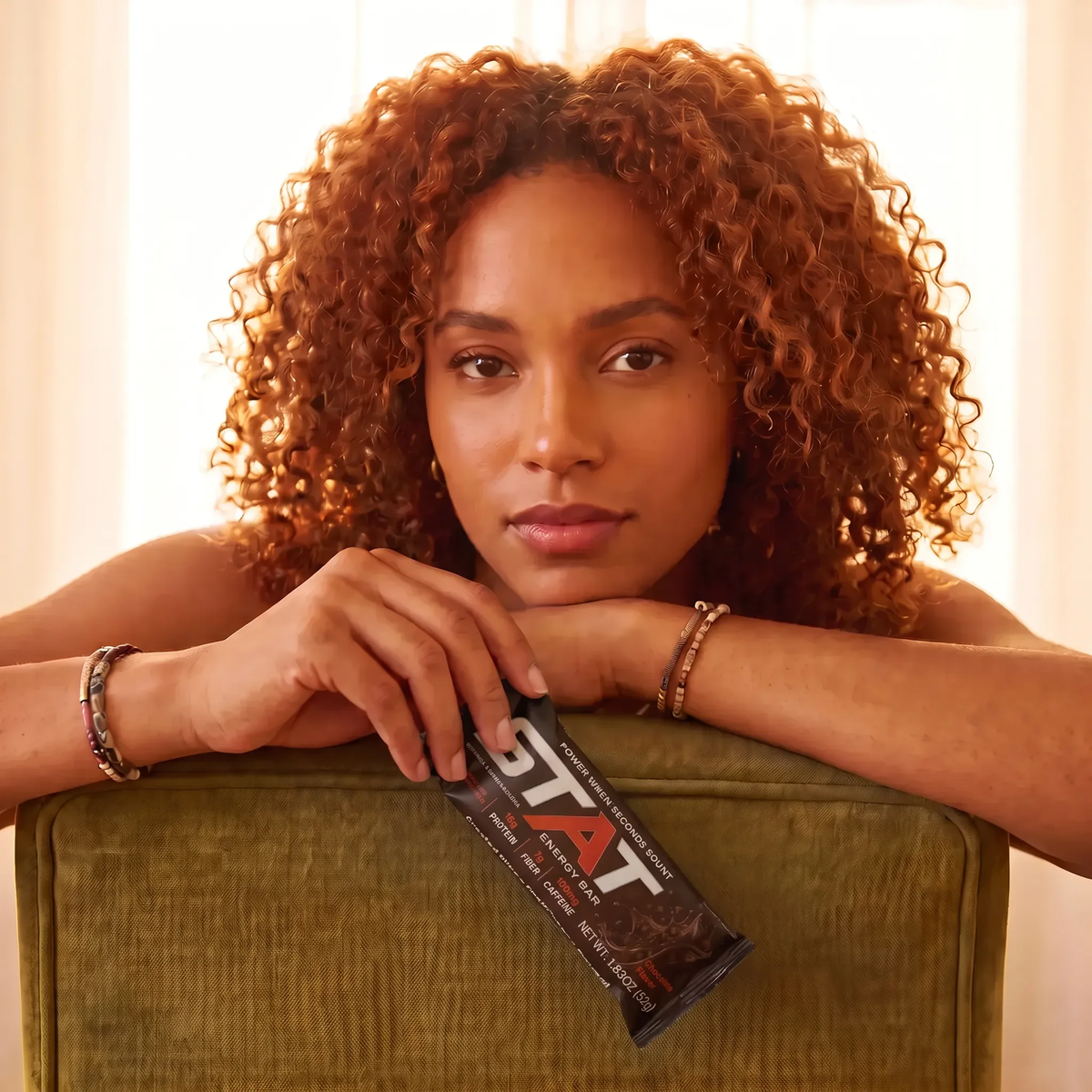 Woman resting on a chair holding a wrapped STAT Chocolate bar