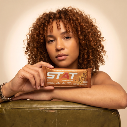 Woman holding a wrapped STAT Peanut Butter Espresso bar
