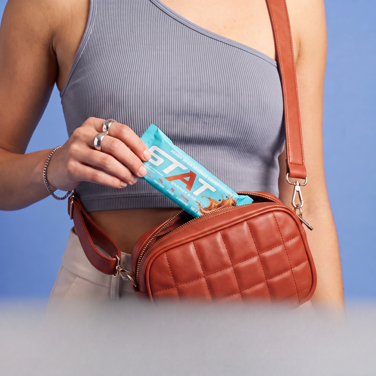 Woman taking a wrapped STAT Salted Caramel Coffee bar out of her crossbody bag