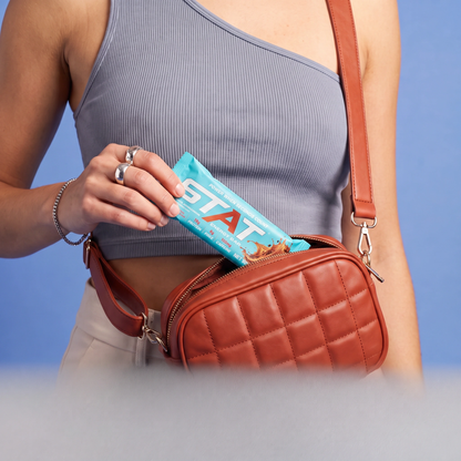 Woman taking a wrapped STAT Salted Caramel Coffee bar out of her crossbody bag
